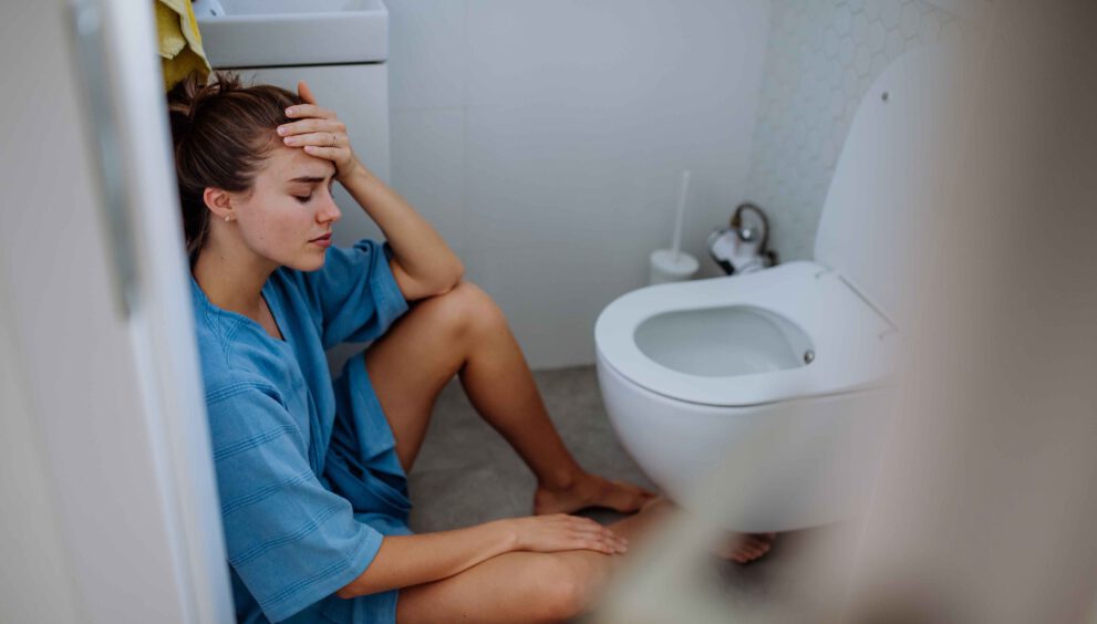 jonge vrouw zit op de grond bij wc overgeven kater.jpg